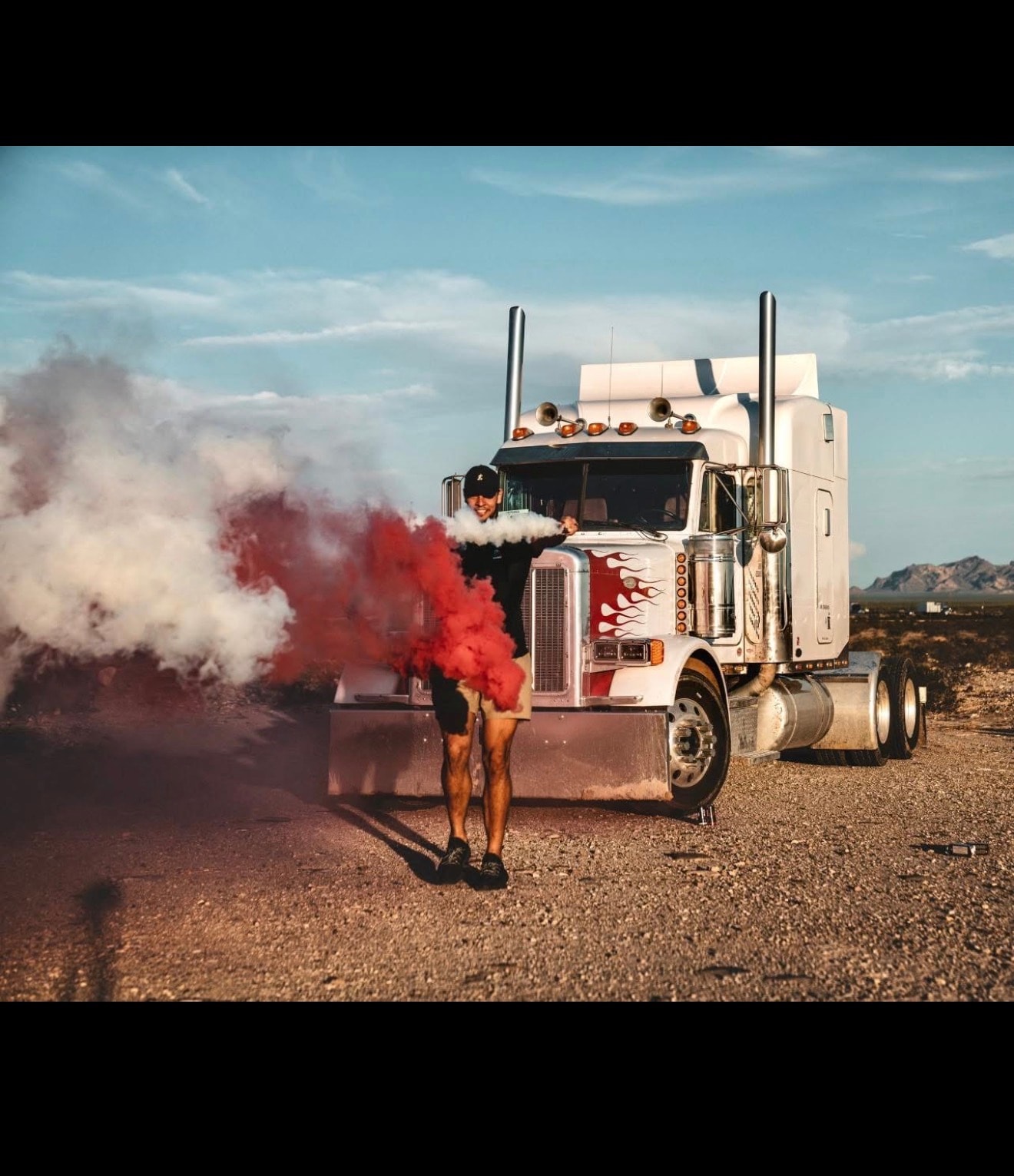 RoadWrench owner standing in front of his Peterbilt semi truck in the Arizona desert with red smoke