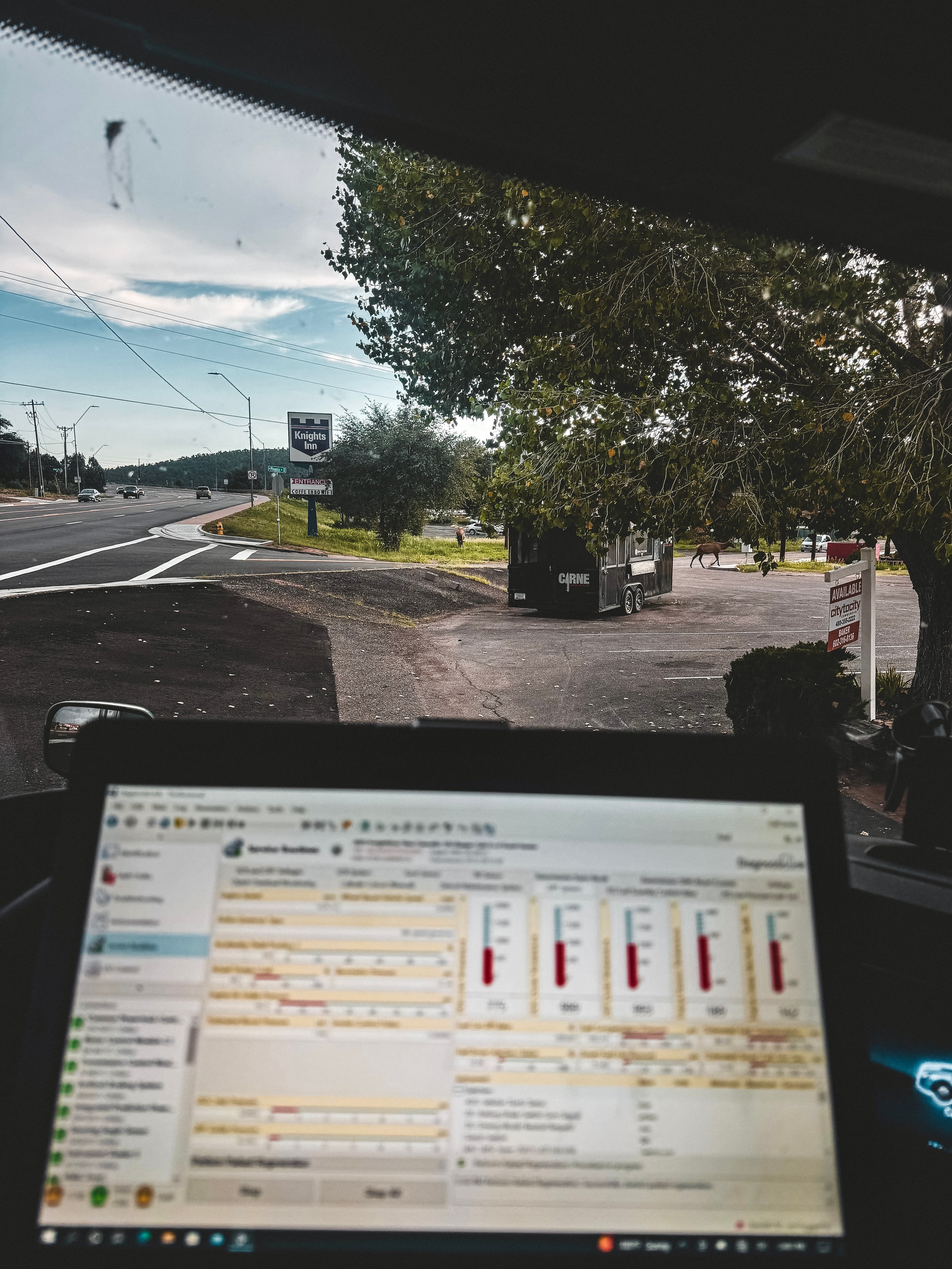 RoadWrench mobile semi truck mechanic running DPF diagnostic software on laptop inside service truck cab — reading Freightliner Cascadia DPF fault codes and emissions data during roadside derate repair near Phoenix AZ