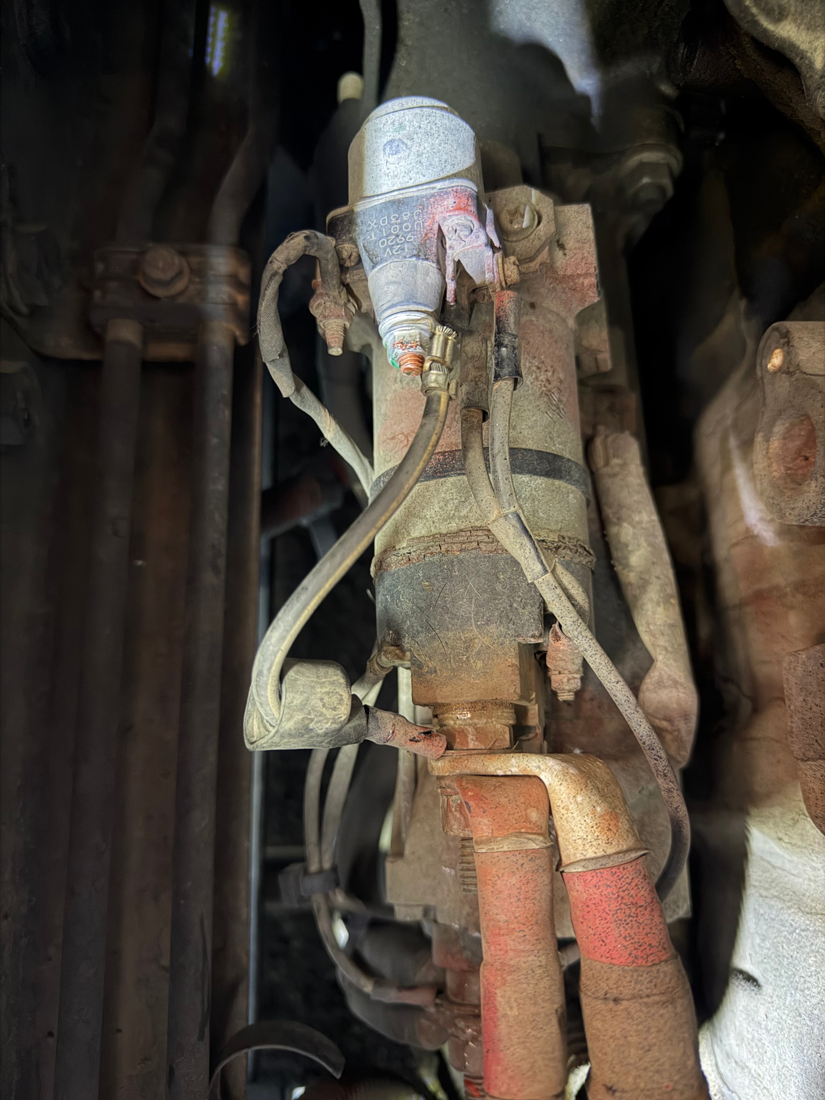 Failed starter motor on Freightliner Cascadia semi truck — worn and corroded starter requiring replacement during mobile roadside repair in Mesa AZ