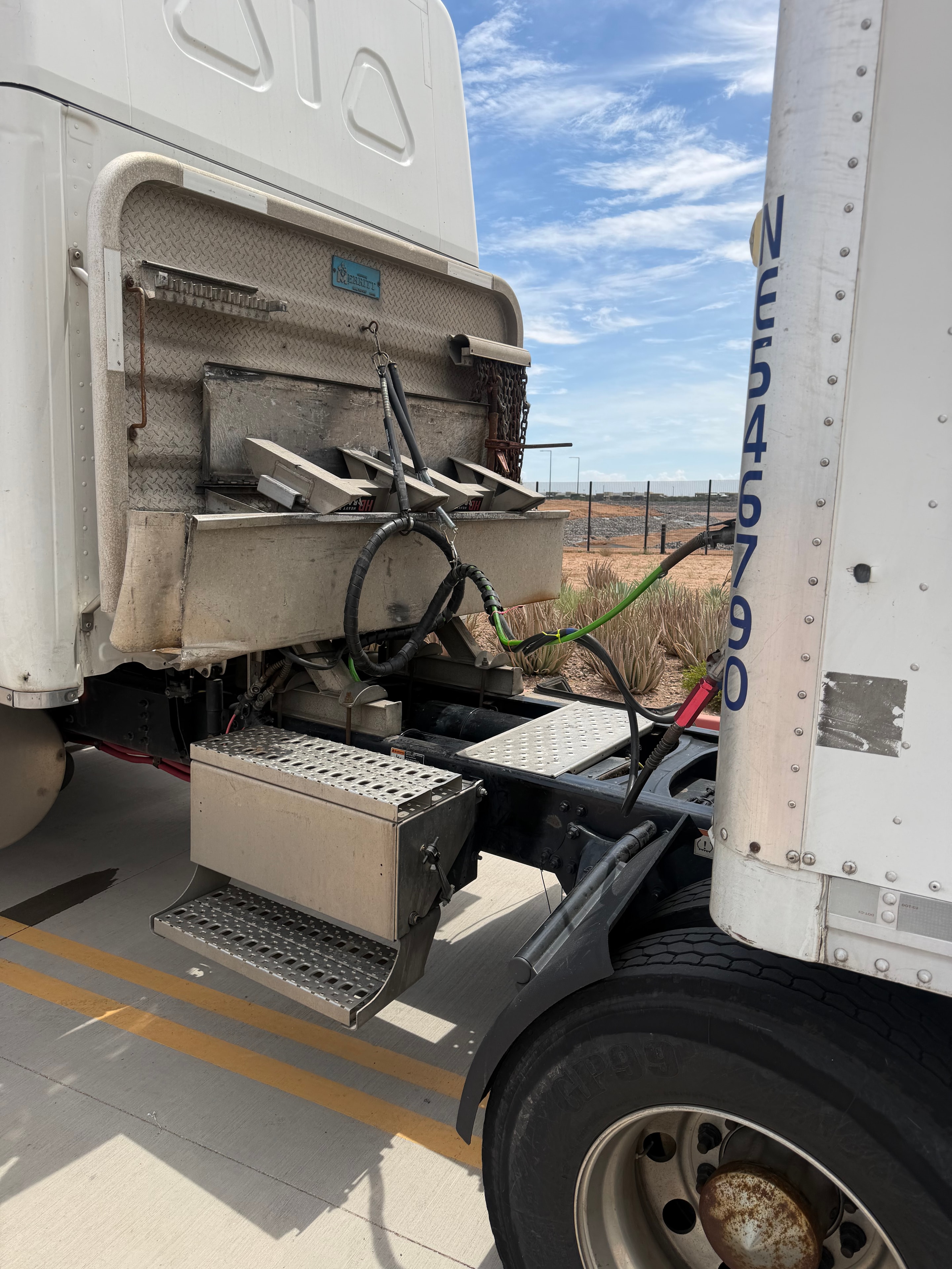 RoadWrench mobile semi truck mechanic repairing ruptured air and electric lines on semi truck and trailer — new green air lines and electrical cables routed and secured at tractor-trailer connection during roadside repair in Gilbert AZ