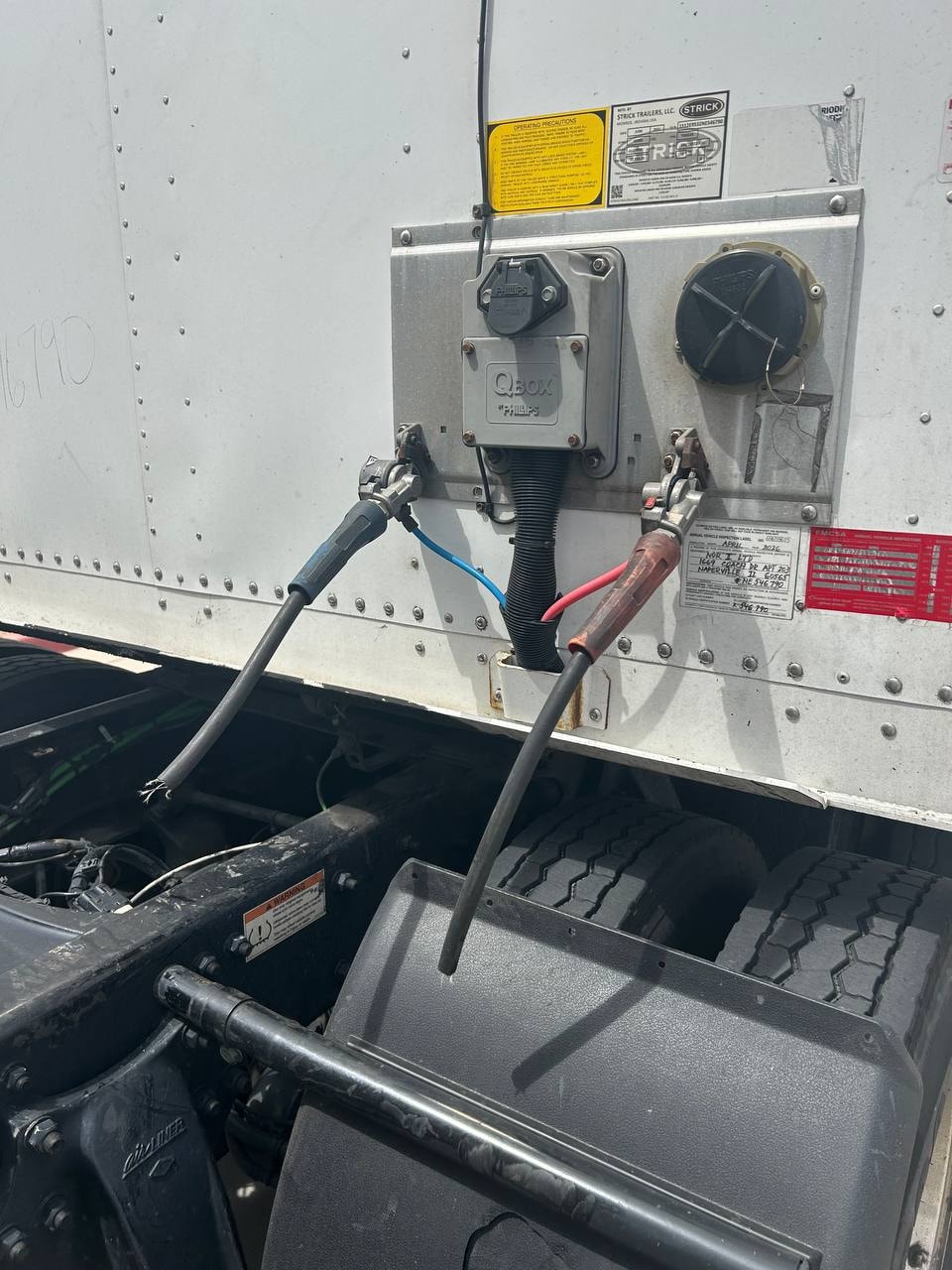 Close-up of completely severed semi truck trailer air line on trailer step — cut black air hose next to new green replacement air line during RoadWrench mobile mechanic repair in Gilbert AZ